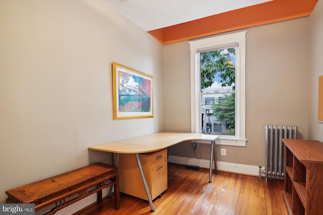 home office with radiator heating unit and hardwood / wood-style flooring