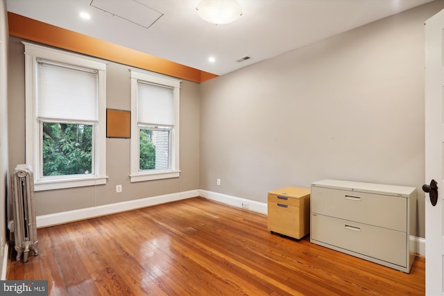 empty room featuring radiator heating unit and light hardwood / wood-style flooring