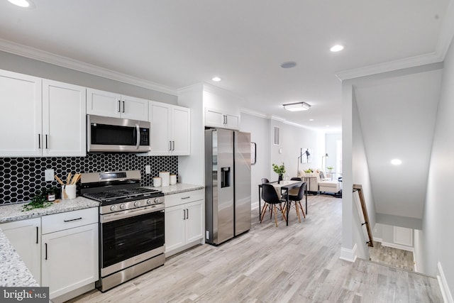 kitchen featuring stainless steel appliances, light hardwood / wood-style floors, tasteful backsplash, ornamental molding, and white cabinetry