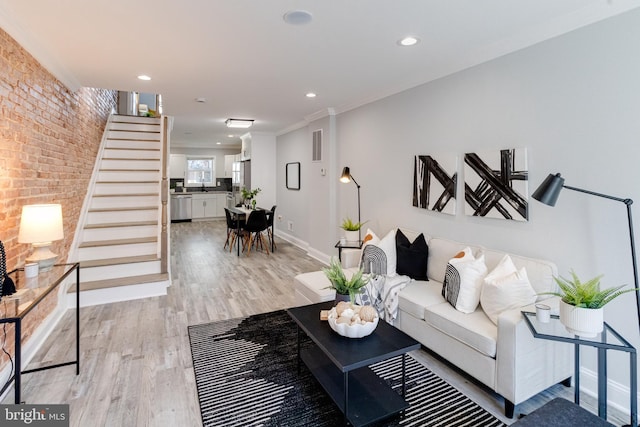 living room featuring brick wall, light wood-type flooring, and ornamental molding