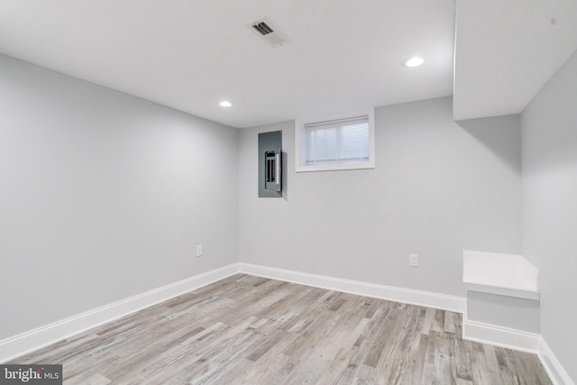 basement with electric panel and light hardwood / wood-style flooring