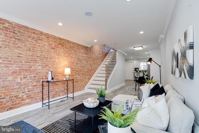 living room with light hardwood / wood-style flooring, brick wall, and crown molding