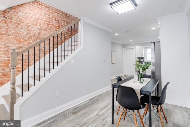 dining room featuring brick wall, light wood-type flooring, and ornamental molding