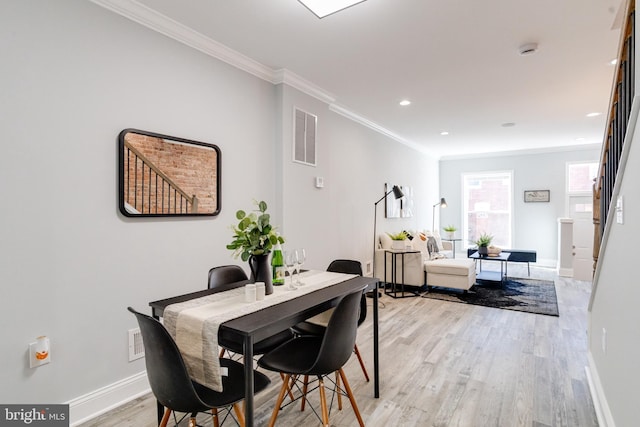 dining space featuring light hardwood / wood-style floors and crown molding