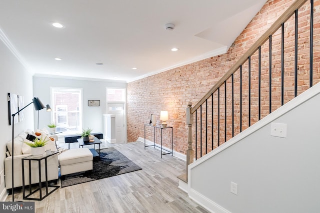 living room featuring brick wall, light wood-type flooring, and ornamental molding