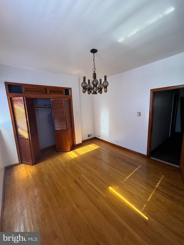 unfurnished dining area with hardwood / wood-style flooring and a chandelier