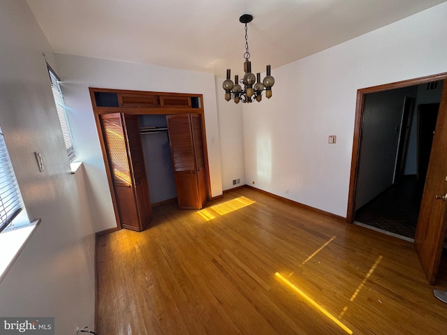 unfurnished dining area featuring an inviting chandelier and hardwood / wood-style flooring