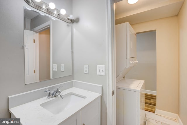 bathroom featuring stacked washer / dryer, vanity, and hardwood / wood-style flooring