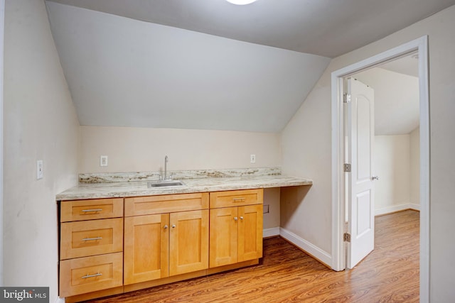 kitchen with light hardwood / wood-style flooring, sink, light stone counters, and vaulted ceiling