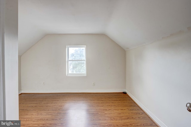 additional living space with light hardwood / wood-style flooring and lofted ceiling