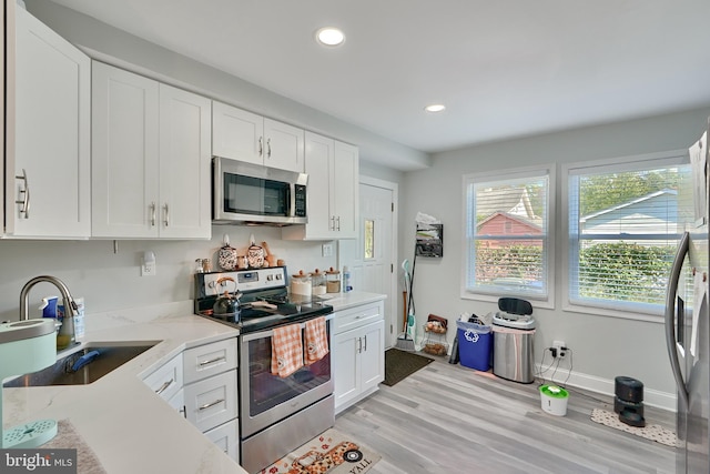 kitchen featuring white cabinets, light stone counters, light wood-type flooring, and appliances with stainless steel finishes