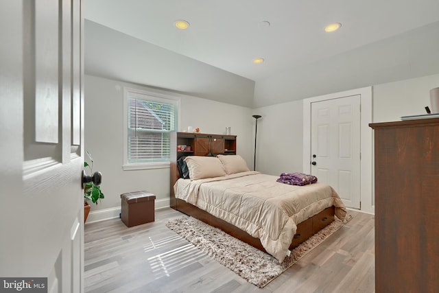 bedroom with light hardwood / wood-style floors and lofted ceiling