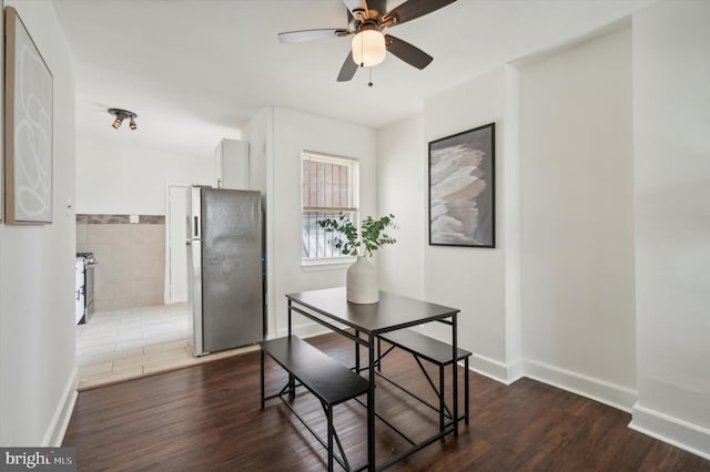 dining area with tile walls, dark wood-type flooring, and ceiling fan