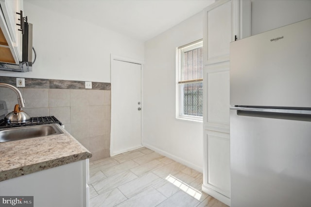 kitchen featuring sink, white refrigerator, and white cabinets