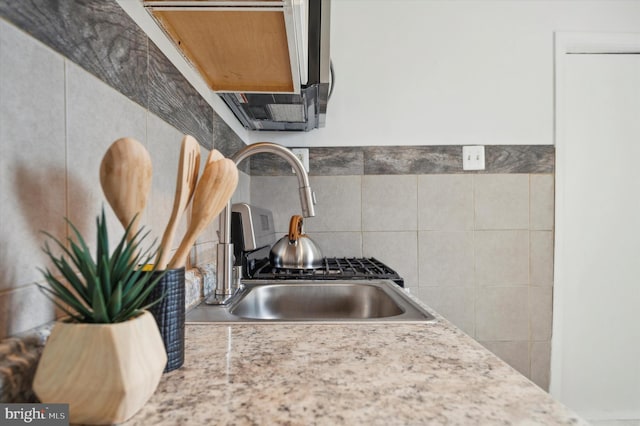 kitchen featuring tile walls, sink, and light stone counters