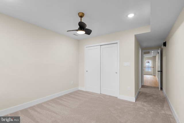 unfurnished bedroom featuring ceiling fan, light carpet, and a closet