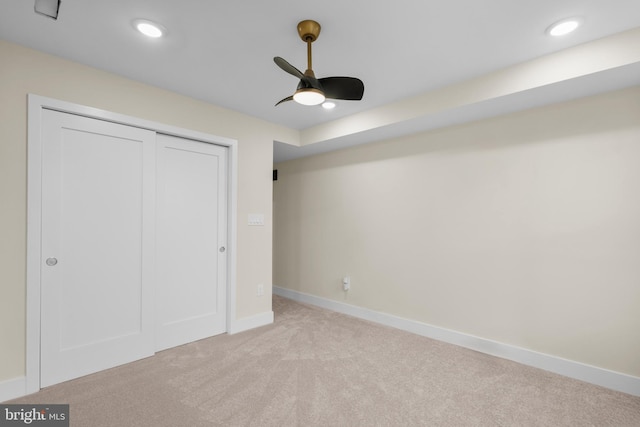 unfurnished bedroom featuring ceiling fan, light colored carpet, and a closet