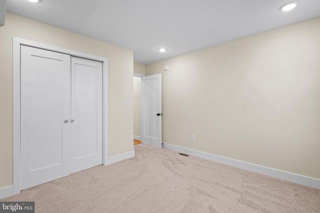 unfurnished bedroom featuring light colored carpet and a closet