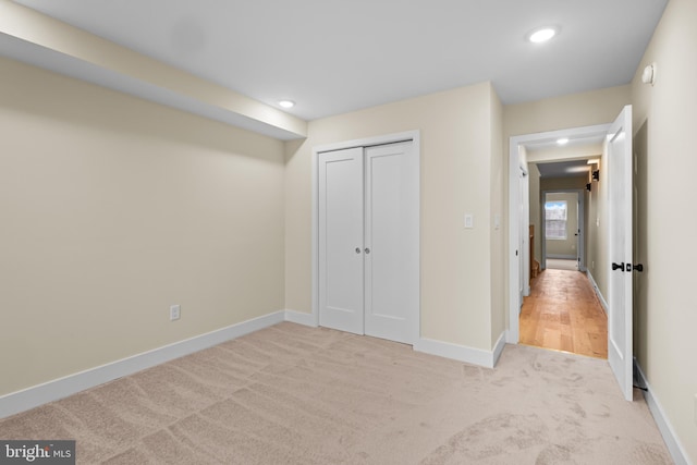 unfurnished bedroom with light carpet and a closet