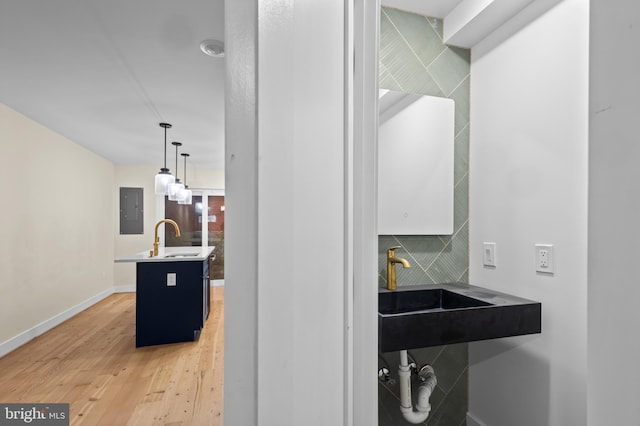 bathroom with hardwood / wood-style flooring, sink, electric panel, and tile walls