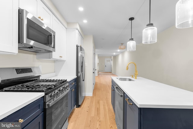 kitchen with appliances with stainless steel finishes, blue cabinets, sink, decorative light fixtures, and white cabinetry