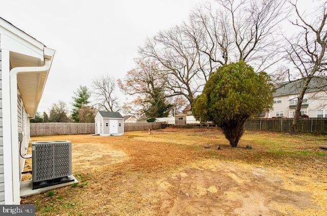 view of yard featuring central AC and a storage unit