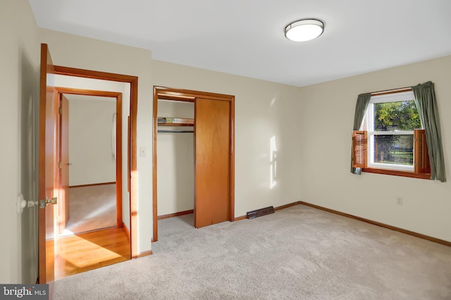 unfurnished bedroom with light carpet and a closet