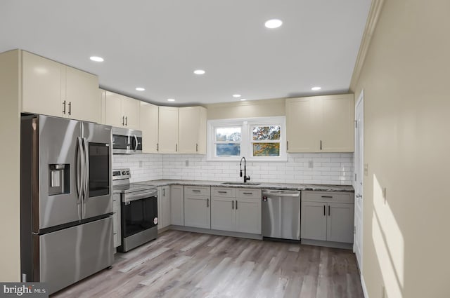 kitchen featuring light hardwood / wood-style floors, crown molding, stainless steel appliances, and sink