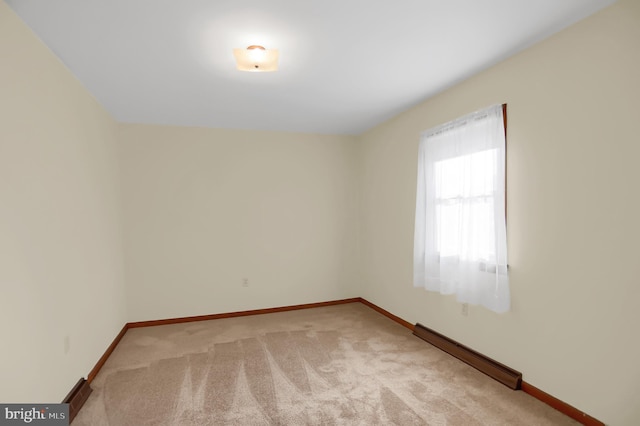 carpeted empty room featuring a baseboard radiator