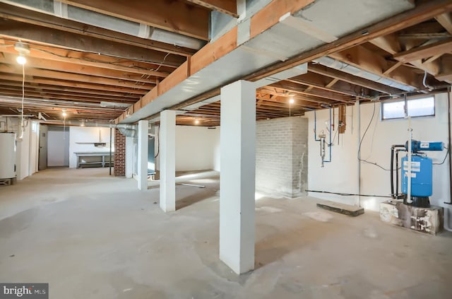 basement featuring brick wall and water heater