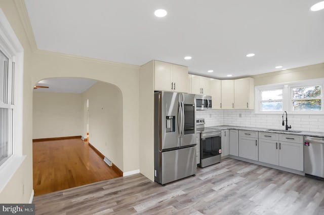 kitchen with light hardwood / wood-style flooring, stainless steel appliances, sink, and crown molding