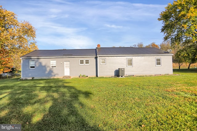 rear view of property featuring a yard and cooling unit