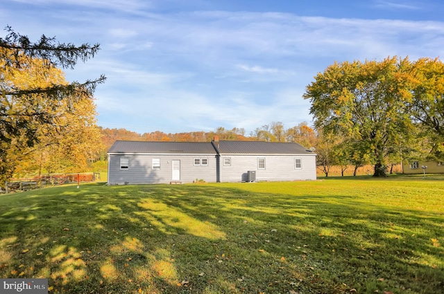 back of property featuring cooling unit and a lawn