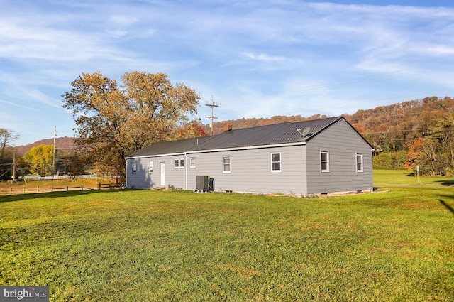 view of side of property featuring cooling unit and a lawn