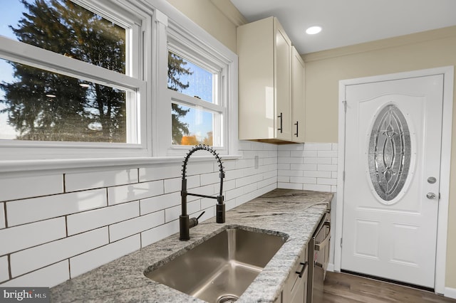 kitchen with hardwood / wood-style flooring, sink, white cabinets, light stone counters, and tasteful backsplash