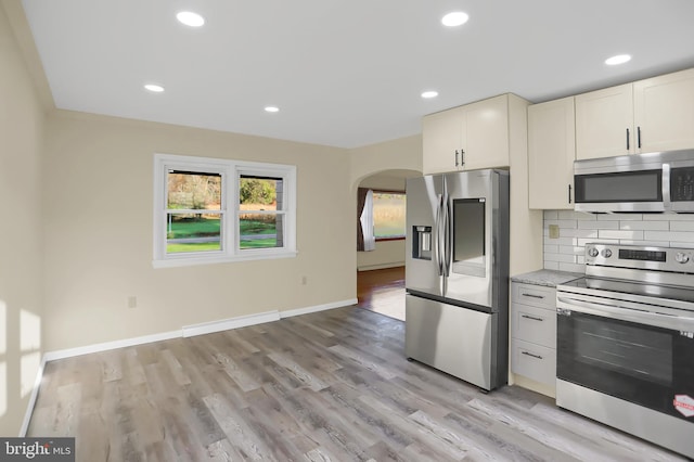 kitchen featuring stainless steel appliances, tasteful backsplash, light wood-type flooring, and white cabinets