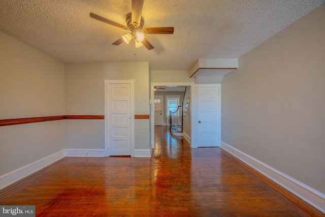 spare room with dark wood-type flooring, a textured ceiling, and ceiling fan