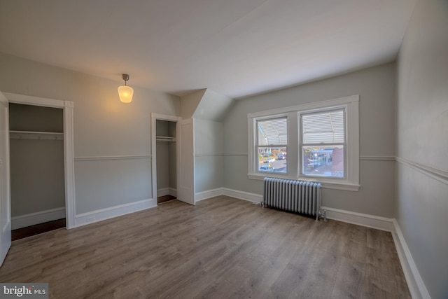 unfurnished bedroom featuring radiator heating unit and hardwood / wood-style floors