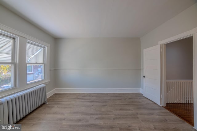 spare room with radiator heating unit and light hardwood / wood-style floors