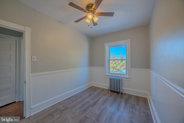 spare room with radiator, light wood-type flooring, and ceiling fan