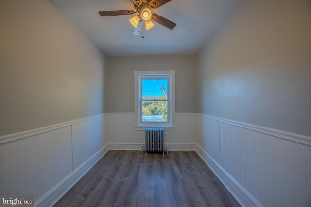 empty room with radiator heating unit, hardwood / wood-style floors, and ceiling fan