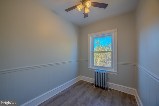 unfurnished room with ceiling fan, radiator, and wood-type flooring