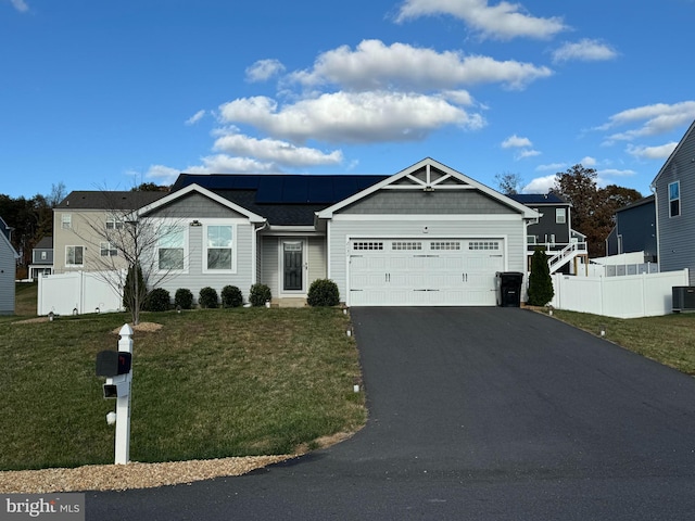 view of front of home with central AC, a garage, solar panels, and a front yard