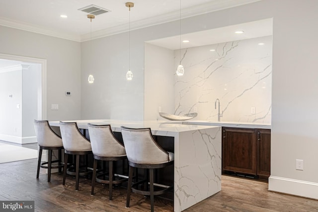 bar featuring decorative light fixtures, dark hardwood / wood-style floors, light stone counters, and ornamental molding