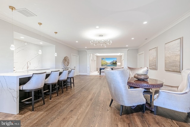 dining room featuring wood-type flooring, an inviting chandelier, and crown molding