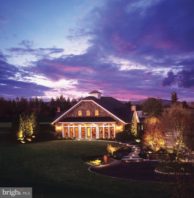 back house at dusk featuring a yard