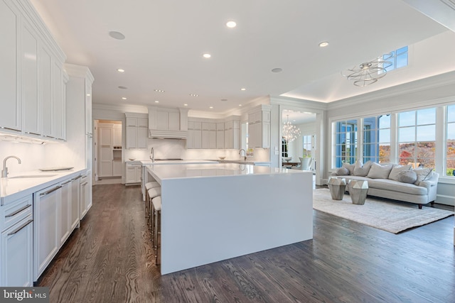 kitchen featuring a breakfast bar, white cabinetry, sink, and dark wood-type flooring