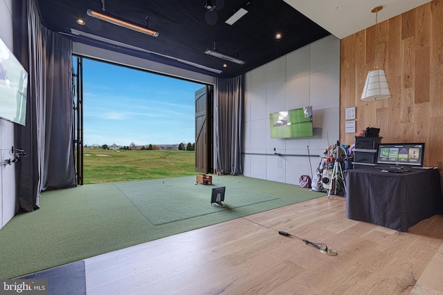 game room featuring hardwood / wood-style floors, golf simulator, and wooden walls