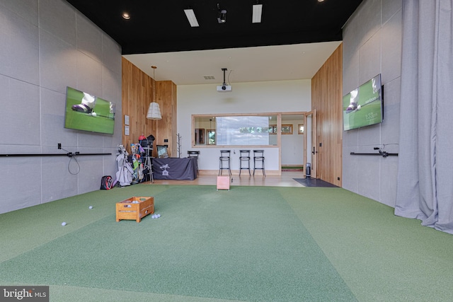 playroom with golf simulator, a high ceiling, and wooden walls