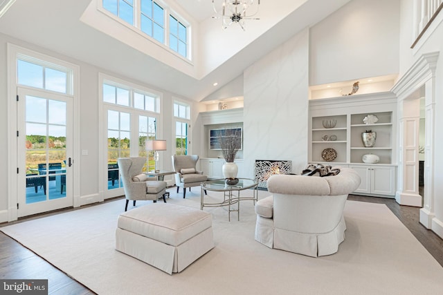 living room with a large fireplace, high vaulted ceiling, wood-type flooring, and an inviting chandelier